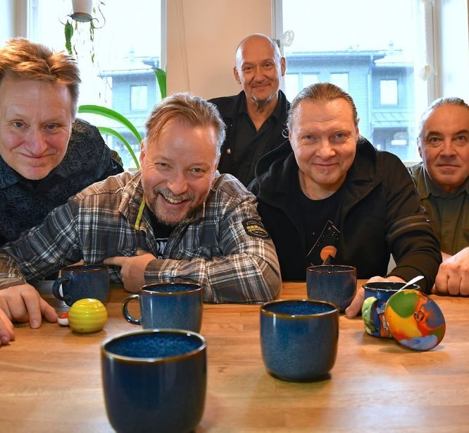 viisi miestä pöydän ääressä