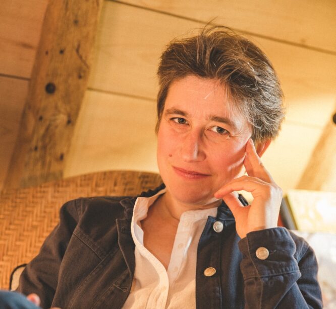 Hymyilevä nainen istuu käsi ohimolla.