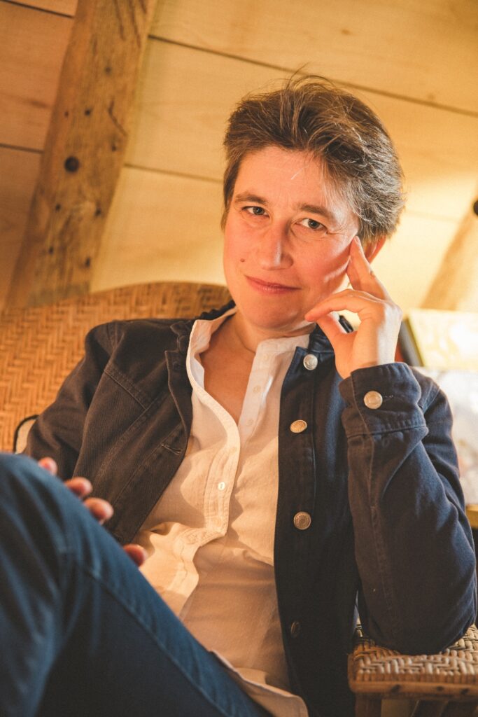 Hymyilevä nainen istuu käsi ohimolla.