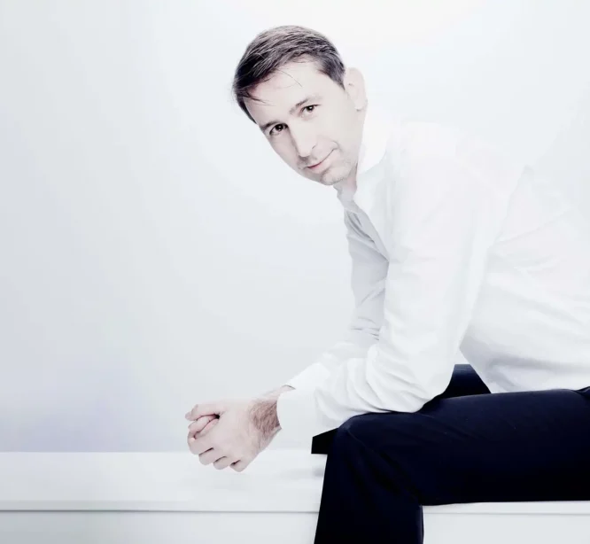 Mies istuu kädet polviin nojaten.