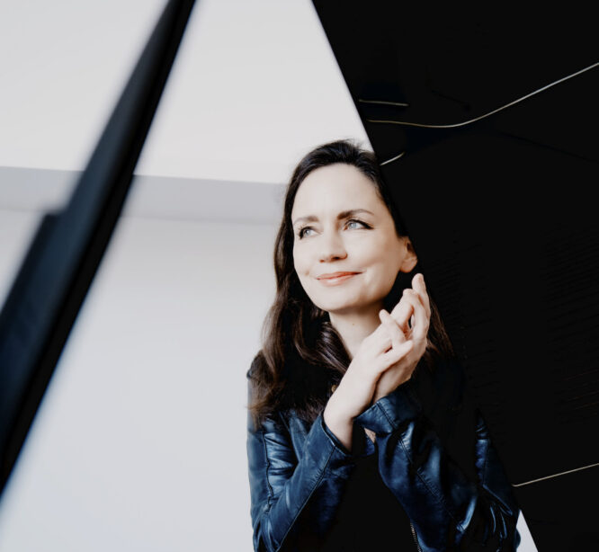 Nainen nojaa flyygeliin.