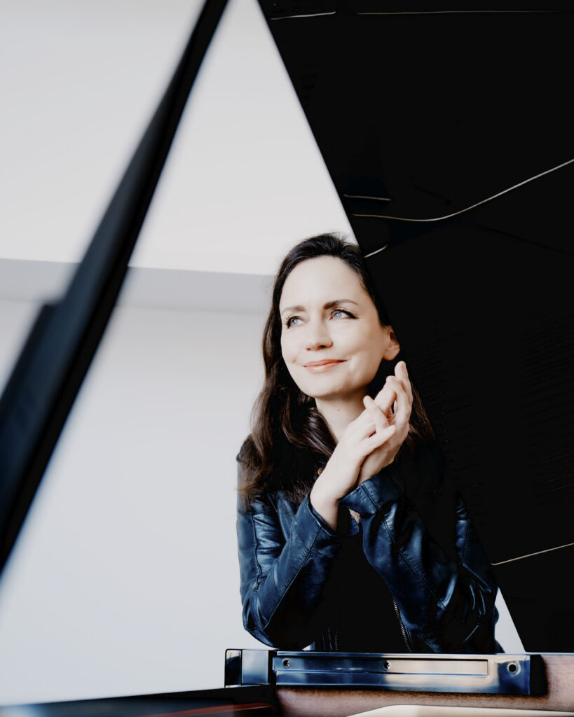 Nainen nojaa flyygeliin.